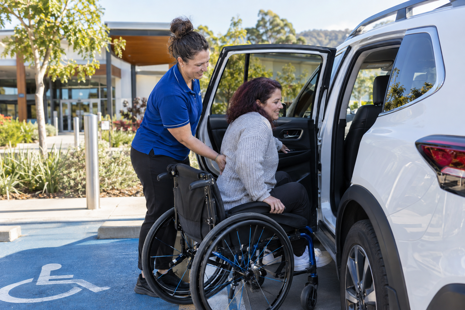 A support worker assisting a wheelchair user to enter a passenger vehicle
